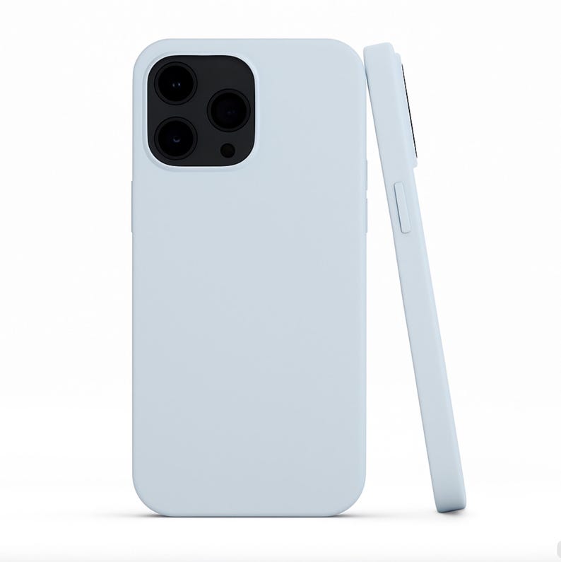 May include: Two light blue phone cases. One case is upright, showcasing the camera cutouts. The other case is leaning against the first, displaying the side buttons. The cases have a smooth, matte finish.