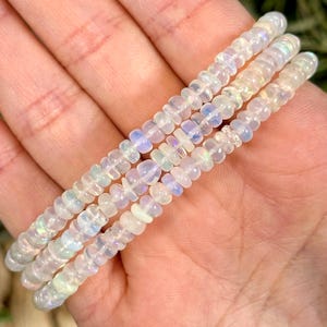 May include: A white opal beaded bracelet with multiple strands of beads. The beads are small and round, and they have a subtle iridescent sheen.