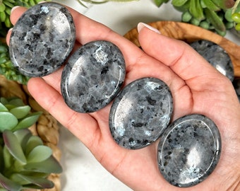 May include: Four smooth, oval-shaped labradorite palm stones. The stones are a dark gray color with iridescent blue and green flashes.