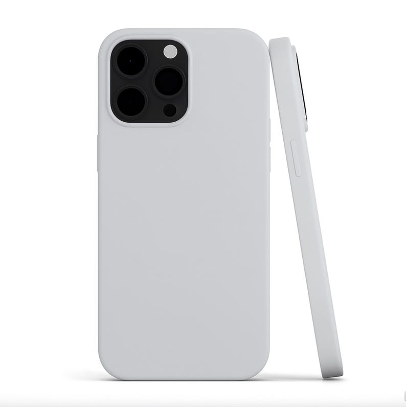 May include: Two white phone cases, one upright and one leaning. The upright case shows the camera cutouts. The cases are a solid, matte white color. The phone cases are designed to protect the phone.