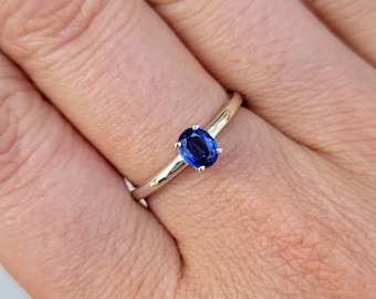 May include: A silver ring with a blue oval-shaped gemstone.