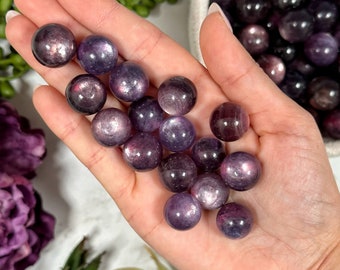Peut inclure: Une collection de 15 sphères de pierres précieuses violettes et irisées. Les sphères sont lisses et polies, avec un effet chatoyant.