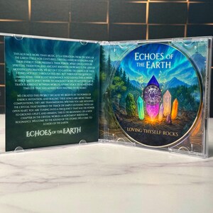 K&ouml;nnte beinhalten: Ge&ouml;ffnete CD-H&uuml;lle mit CD und Innenseite. Die CD zeigt eine farbenfrohe Illustration von Kristallen und einer Berglandschaft. Die Texte "Echoes of the Earth" und "Loving Thyself Rocks" sind sichtbar. Die Innenseite enth&auml;lt Text &uuml;ber das Album.