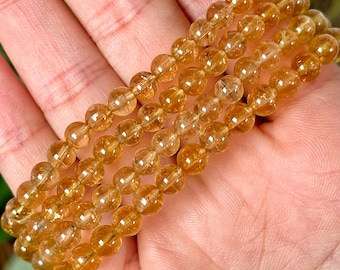 May include: A stack of four bracelets made with golden yellow citrine beads. The beads are round and smooth, and the bracelets are strung on elastic.