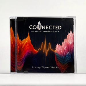 May include: A CD case with the title "CONNECTED" and the subtitle "A CRYSTAL PAIRINGS ALBUM" in white text. The cover features a dark background with orange, red, and pink crystal formations and a central waveform design. The text "Loving Thyself Rocks" is at the bottom.