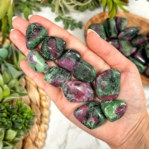 May include: A collection of green and pink tumbled stones. The stones are smooth and polished, with a variety of patterns and textures.