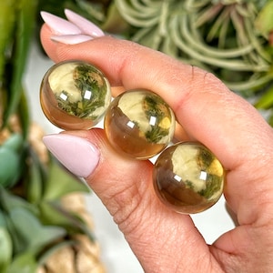 Puede incluir: Tres esferas de cristal transparentes, de color amarillo dorado, con inclusiones. Las esferas son lisas y pulidas.