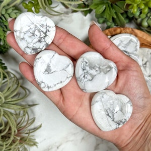 May include: Four white heart-shaped stones with gray veining. The stones are smooth and polished.