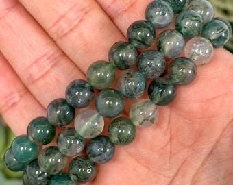 May include: A bracelet made of green moss agate beads. The beads are round and have a natural, earthy look.