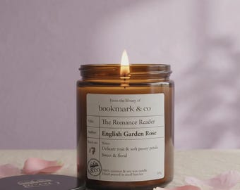 Peut inclure: Une bougie allumée dans un pot en verre ambré avec une étiquette blanche indiquant From the library of bookmark & co, Title: The Romance Reader, Author: English Garden Rose, Notes: Delicate rose & soft peony petals, Sweet & floral, 290g.