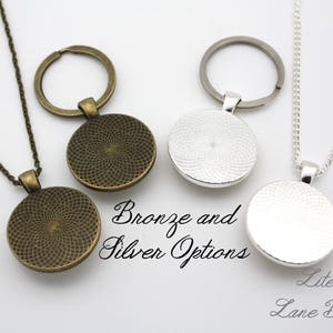 Pode incluir: Dois colares com um pingente circular, um de bronze e outro de prata. Os pingentes t&ecirc;m um design texturizado. Os colares est&atilde;o sobre um fundo branco. Op&ccedil;&otilde;es de bronze e prata. Literary Lane Boutique.
