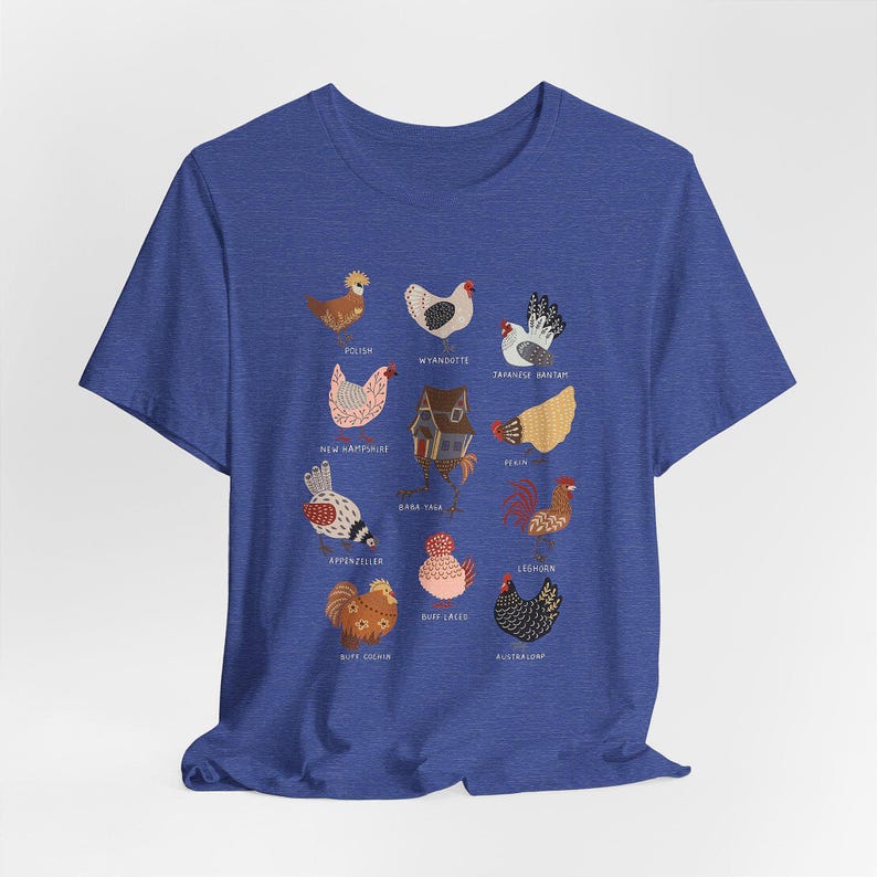 May include: Blue t-shirt featuring a colorful illustration of various chicken breeds, each labeled with its name. The design includes breeds like Polish, Wyandotte, and Japanese Bantam, among others. The shirt is made of a soft material.
