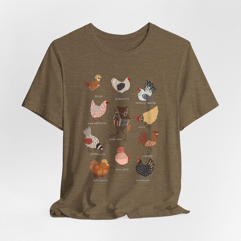 May include: A brown t-shirt featuring a colorful illustration of various chicken breeds, each labeled with its name. The design includes breeds like Polish, Wyandotte, and Japanese Bantam, among others. The artwork is detailed and whimsical, perfect for poultry enthusiasts.
