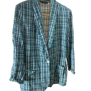 May include: A plaid blazer in shades of blue, green, and white. The blazer has a single-button closure, two front pockets, and a notched lapel. The interior lining features a plaid pattern in brown, tan, and purple.
