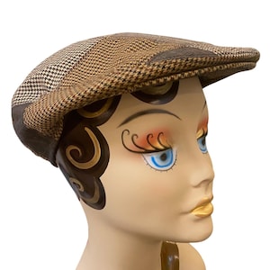 May include: A brown and tan plaid newsboy cap. The cap features a classic design with a rounded crown and a short, stiff brim. The fabric has a textured appearance, with a mix of brown and tan tones.