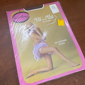 Peut inclure: Emballage vintage de bas "Hi on the Thi" de Ruth Barry. L'emballage rose et jaune présente une femme en porte-jarretelles. Les bas sont de couleur pécan, taille 9½-10.