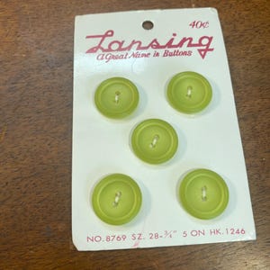 May include: A card of five round, light green buttons. The card reads "Lansing, A Great Name in Buttons" and includes the price "40¢". The buttons are approximately 28-3/4 inches in size.