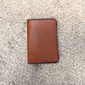 May include: A brown leather wallet with a stitched edge.