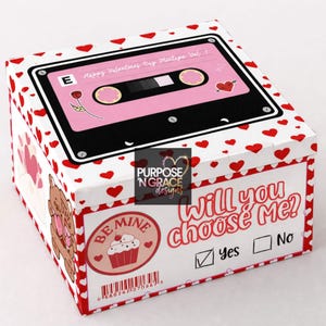 May include: A white box decorated with red hearts and a pink cassette tape design. The box features the text "Happy Valentines Day Mixtape Vol. 1" and "Will you choose Me?" with a check box next to "Yes".