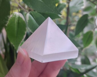 Puede incluir: Un cristal de pirámide de selenita blanca, un tipo de mineral conocido por sus propiedades calmantes y purificantes.