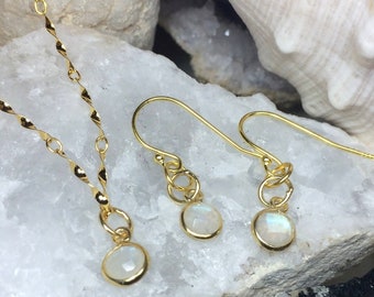 Puede incluir: Un conjunto de joyas de color dorado que incluye un collar y pendientes. El collar tiene una cadena retorcida con un pequeño colgante redondo de piedra blanca. Los pendientes tienen un diseño similar, con una piedra preciosa blanca.