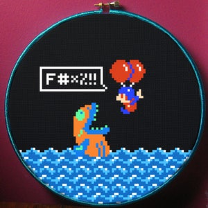 May include: A black and white pixel art cross-stitch embroidery hoop with a blue, orange, and green creature in the water. The creature is saying "F**k!!!" in a speech bubble. A red and blue character is floating above the water with two red balloons.