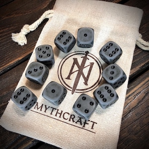 May include: A set of ten gray dice with black pips, displayed on a tan cloth bag. The bag features a logo and the word "MYTHCRAFT" printed in brown. The dice are arranged around the bag on a wooden surface.
