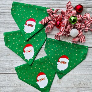 May include: Four green dog bandanas with gold stars and a white Santa Claus face with a red hat.