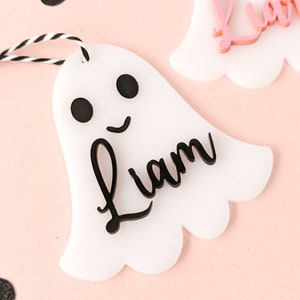May include: White ghost-shaped ornament with a black outline and black eyes. The ornament has the name "Liam" written in black cursive lettering.
