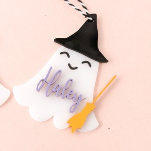 May include: White ghost ornament with a black witch hat, purple name "Haley" and a yellow broom.
