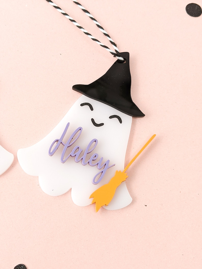 May include: White ghost ornament with a black witch hat, purple name "Haley" and a yellow broom.