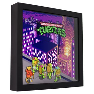 May include: A framed pixel art print of the Teenage Mutant Ninja Turtles from the classic video game. The turtles are standing on a rooftop in a city skyline with a building on fire in the background. The title "Teenage Mutant Ninja Turtles" and "TURTLES" are displayed in the image.