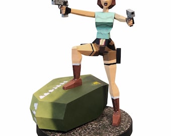 May include: A low-poly papercraft figurine of a character with brown hair, wearing a light blue tank top, brown shorts, and brown boots. The figure holds two grey handguns and stands with one foot on a large green block on a circular base.