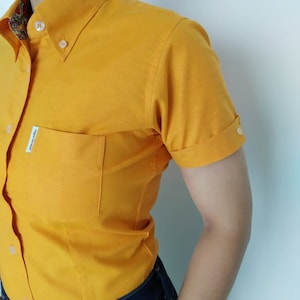 Peut inclure: Une chemise boutonn&eacute;e &agrave; manches courtes de couleur jaune avec une seule poche sur la poitrine gauche. La chemise a un col boutonn&eacute; et une petite &eacute;tiquette sur la poche qui indique "Jack & Jones".
