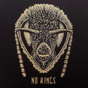 May include: A detailed gold illustration of an insect head on a black background. The insect's head is intricately drawn with fine lines, showcasing its antennae, eyes, and mouthparts. The text "NO KINGS" is written in gold at the bottom.