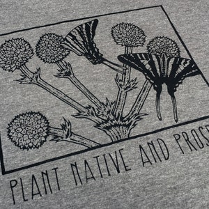 May include: Gray t-shirt featuring a black and white illustration of butterflies and thistle-like flowers within a square frame. The text "PLANT NATIVE AND PROSPER" is printed below the frame in a sans-serif font.