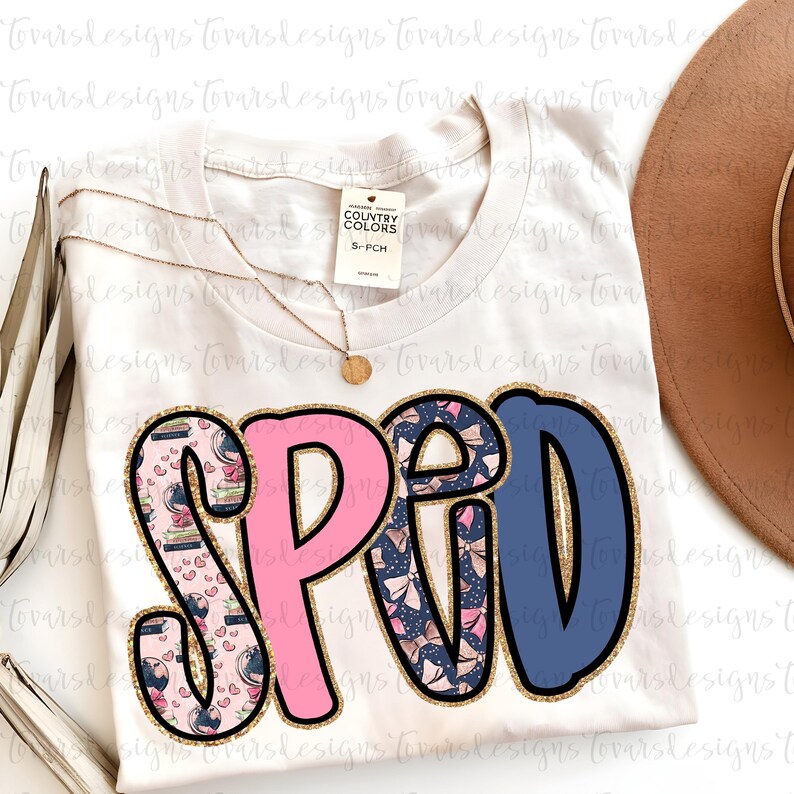 K&ouml;nnte beinhalten: Ein cremefarbenes T-Shirt mit dem Wort "SPED" in gro&szlig;en Buchstaben. Die Buchstaben sind rosa und blau mit goldfarbenem Glitzerbesatz. Das "S" und das "D" sind mit B&uuml;chern und Herzen gemustert. Eine goldene Halskette und ein brauner Hut sind ebenfalls zu sehen.