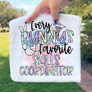 May include: White sweatshirt with a colorful graphic that reads "Every Bunny's Favorite Skills Coordinator." The design includes a bunny, stethoscope, and medical symbol. The text is in various pastel colors.