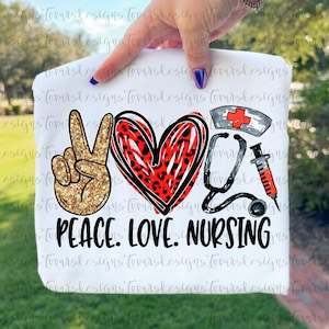 May include: A white t-shirt featuring a graphic design with a gold glitter peace sign, a red leopard print heart, a nurse cap with a red cross, a black stethoscope, and a syringe. The text reads PEACE. LOVE. NURSING in bold black capital letters.