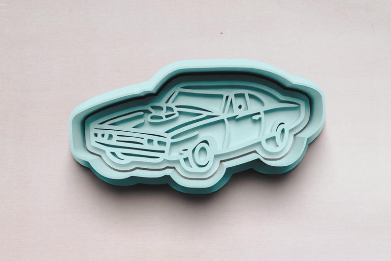 May include: A light blue plastic cookie cutter shaped like a classic muscle car. The car has a detailed design with a hood scoop and wheels.