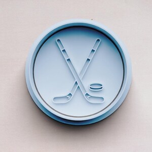 May include: A blue plastic cookie cutter shaped like a hockey stick and puck.