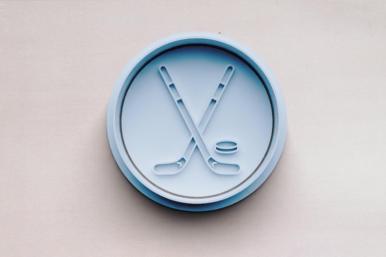 May include: A blue plastic cookie cutter shaped like a hockey stick and puck.