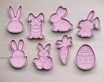 May include: Set of eight pink plastic cookie cutters shaped like Easter bunnies, carrots, and eggs. The cutters are designed for making cookies, fondant, or other edible treats.