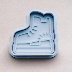 May include: A light blue plastic cookie cutter shaped like an ice skate.