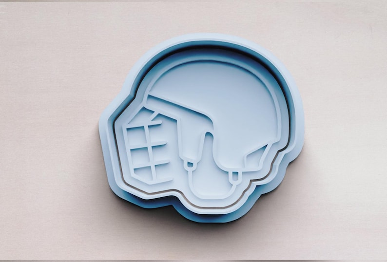 May include: A light blue plastic cookie cutter shaped like a hockey helmet.