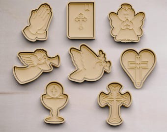 May include: Set of nine cookie cutters with religious themes, including a dove, a heart with a cross, a chalice, a cross, a praying angel, a book with a cross, and two praying hands.