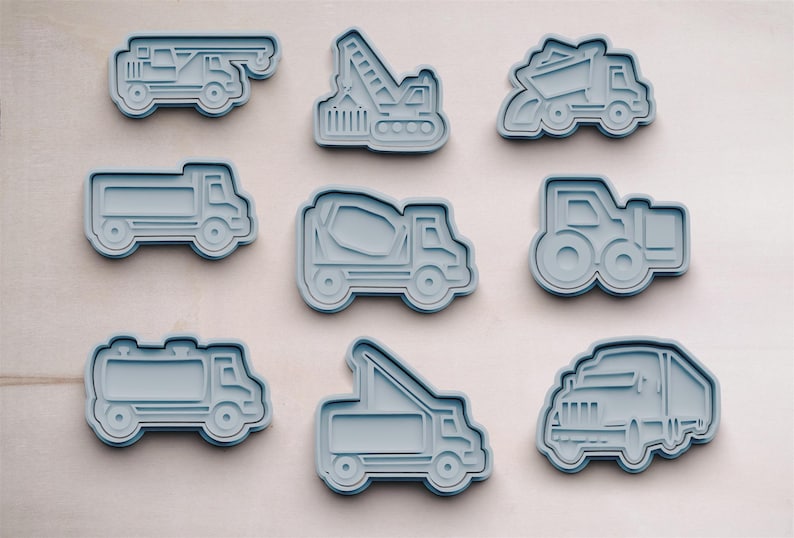 以下が含まれることがあります： 建設車両の形をした青いプラスチック製のクッキー型が9個あります。型には、セメントミキサー、ダンプトラック、クレーン、セミトレーラー、ブルドーザー、ピックアップトラックが含まれています。