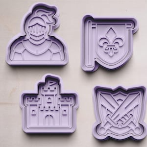 May include: Four purple plastic cookie cutters shaped like a knight, a castle, a shield with swords, and a flag with a fleur-de-lis.