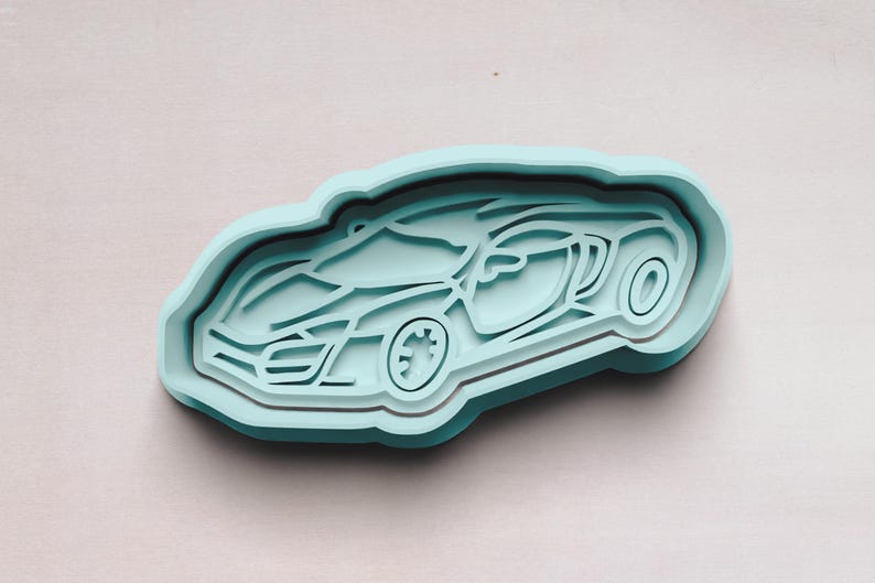 May include: A light blue plastic cookie cutter shaped like a sports car. The car is facing to the right and has a detailed design.
