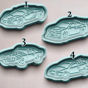 May include: Four different cookie cutters shaped like cars. The cutters are made of light blue plastic and are numbered 1 through 4.